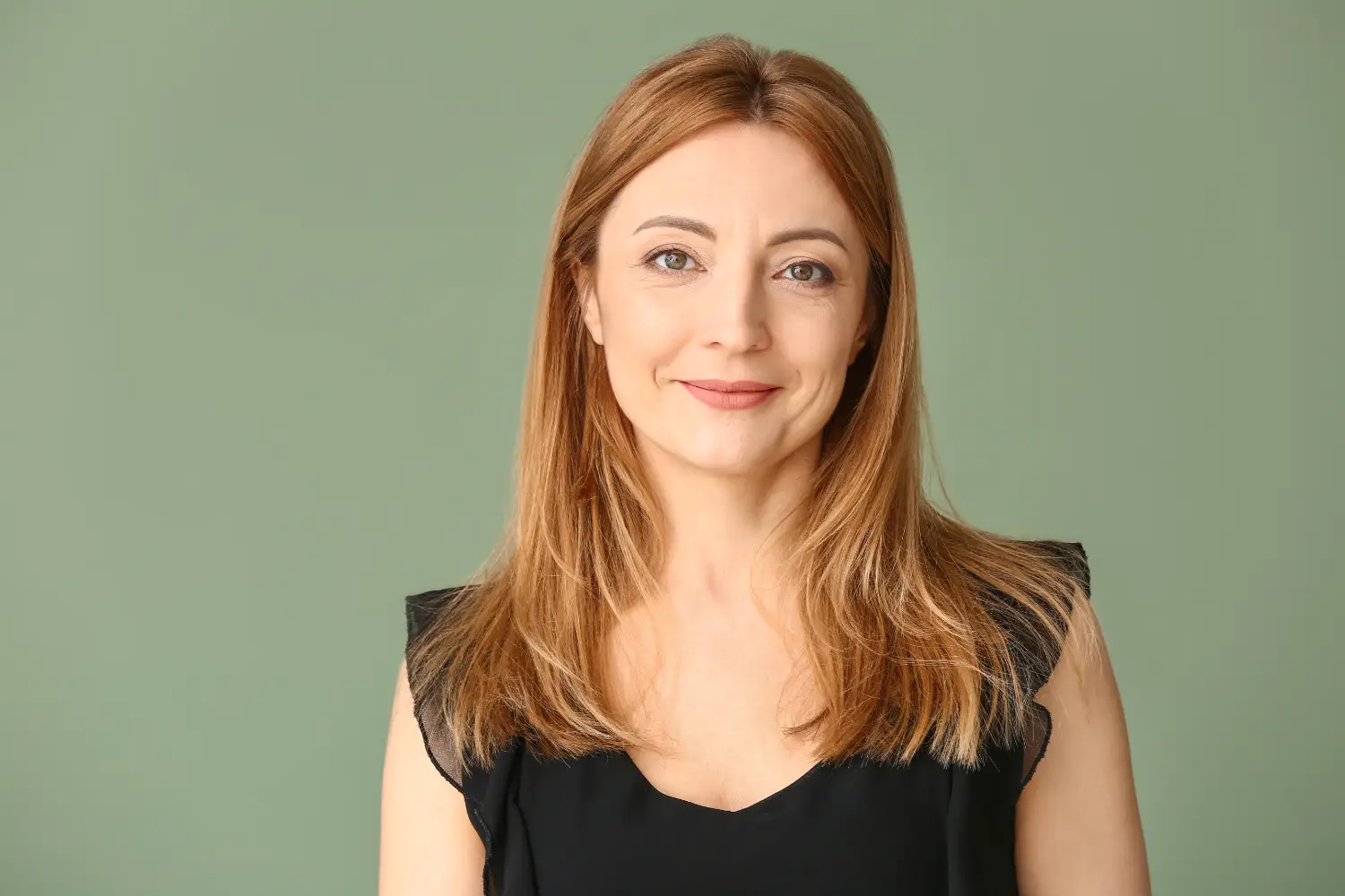 woman with shoulder-length hair wearing a black top against a green background