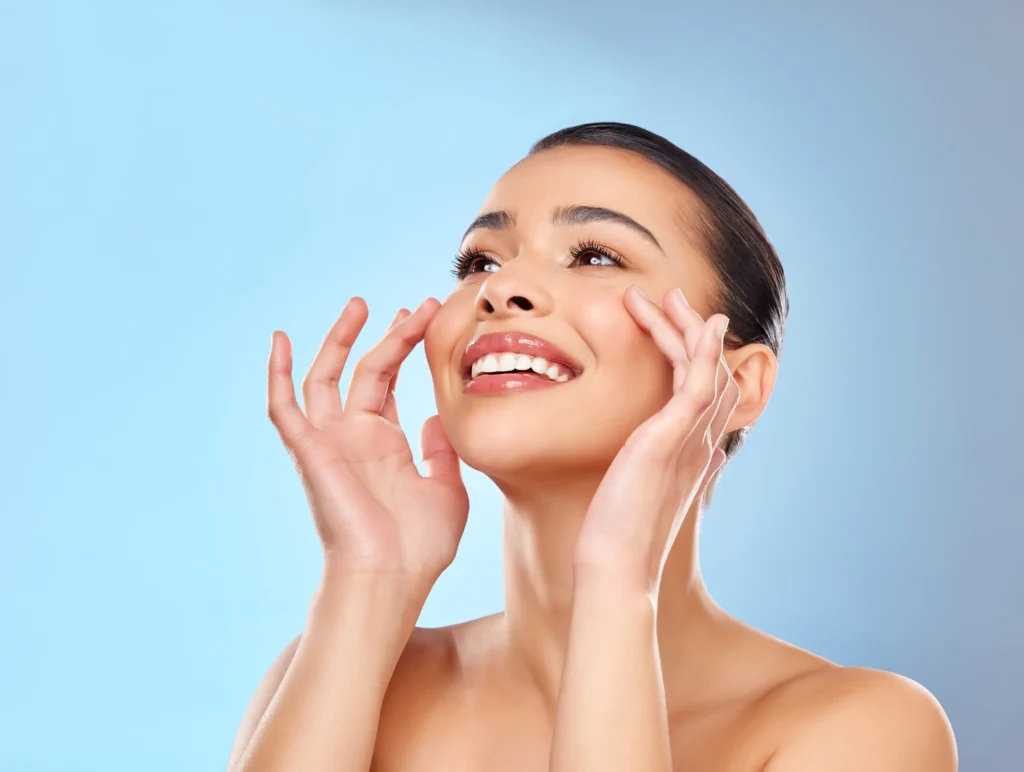 Woman smiling and touching her cheeks against a blue background