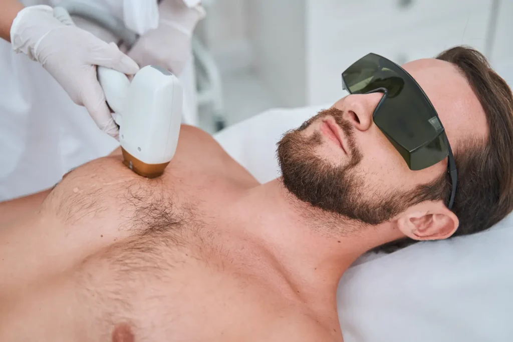 Practitioner applies a handheld laser device to a person's chest while the person wears protective eyewear.