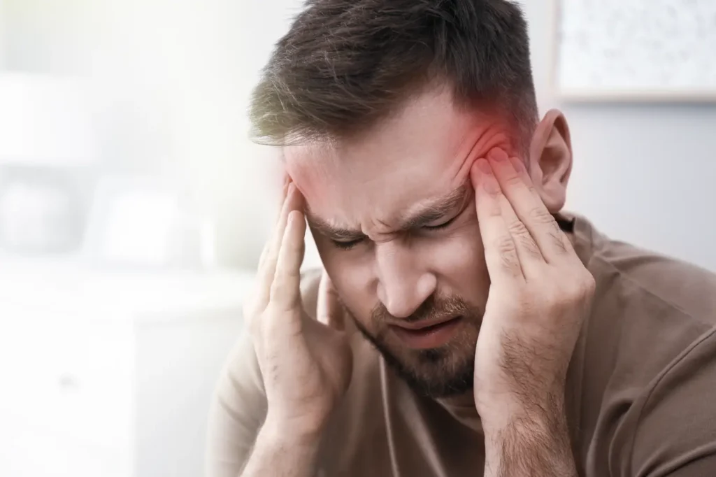 Man closes his eyes and presses both hands against his temples.