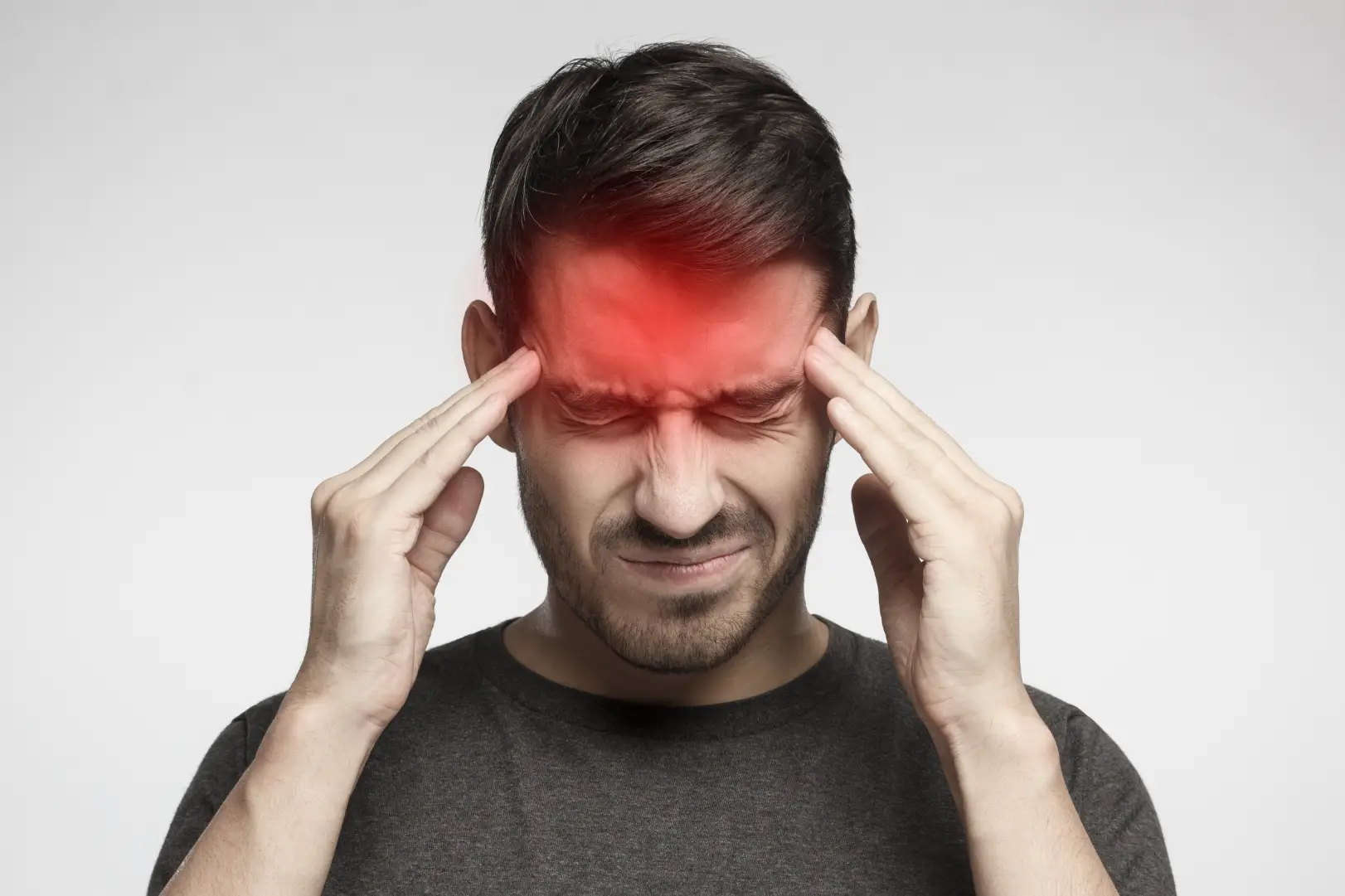 an presses both temples with eyes closed as a red highlight covers his forehead.